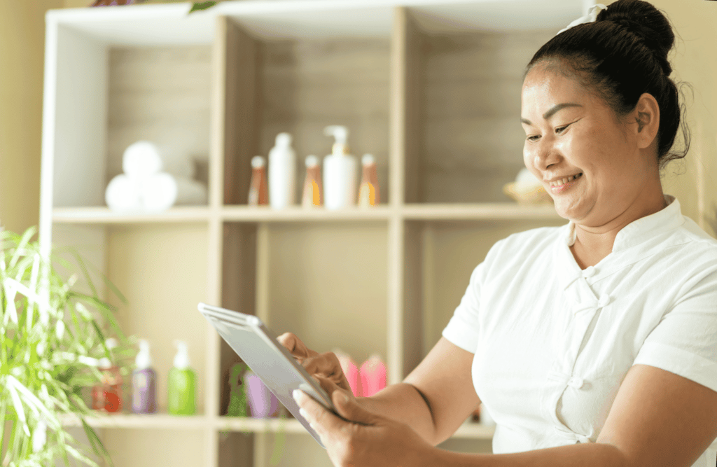 beauty salon professional in white using a tablet with beauty products on the backdrop