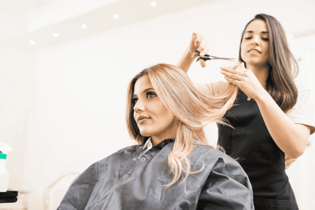 hairdresser cutting hair of a client in a salon with a scissor 