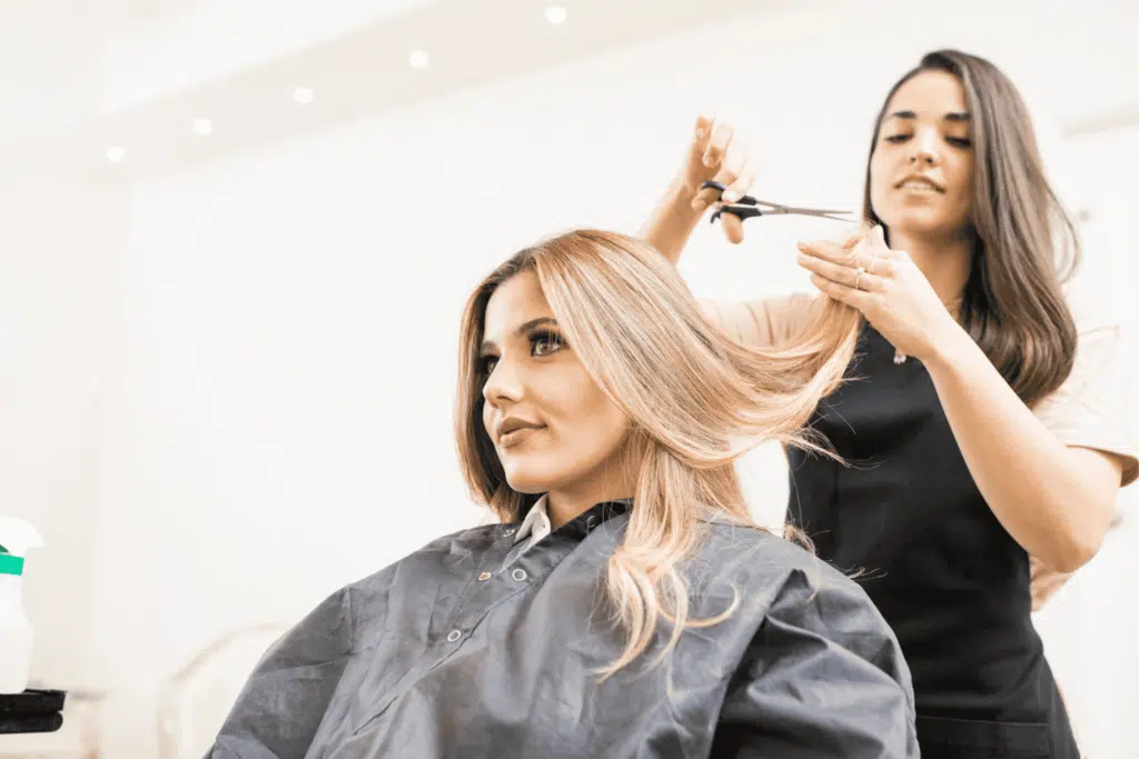 hairdresser cutting hair of a client in a salon with a scissor