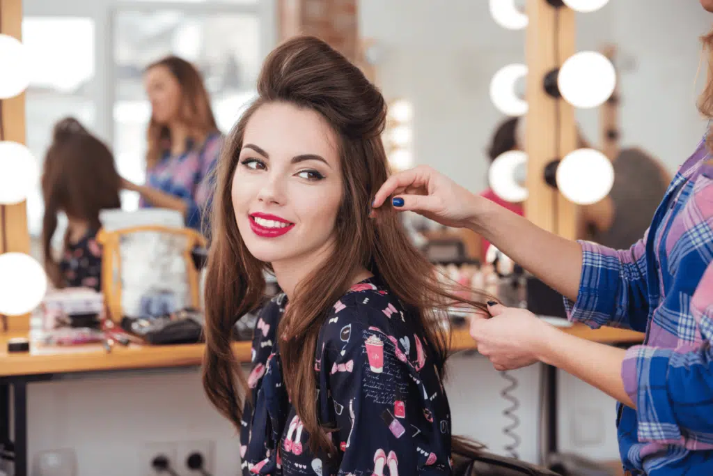 Female hairdresser making hairstyle to woman in beauty salon