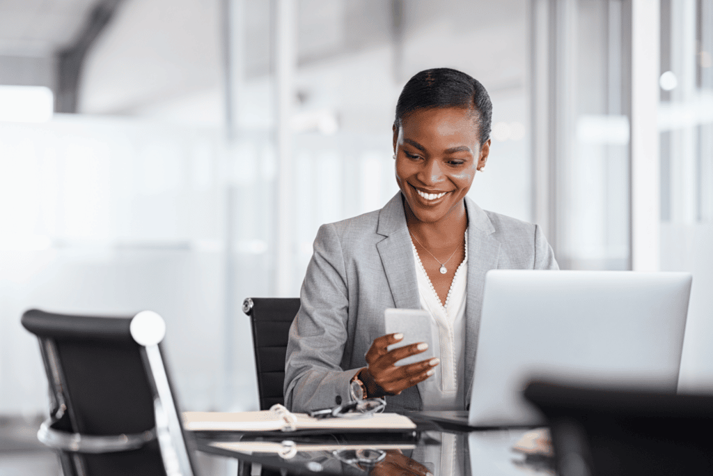 woman sending business text in white office with laptop and notebook on a table