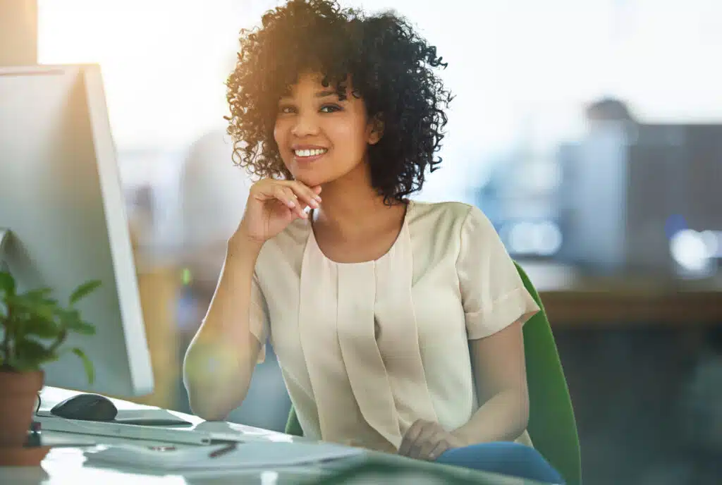 admin staff smiling with computer in office setting