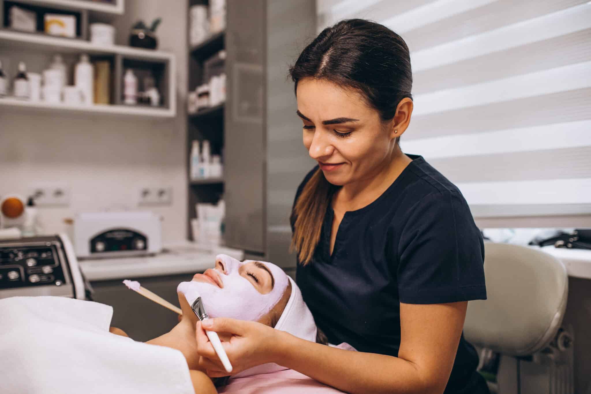 esthetician working on cosmetology mask application on a face of client in a beauty salon