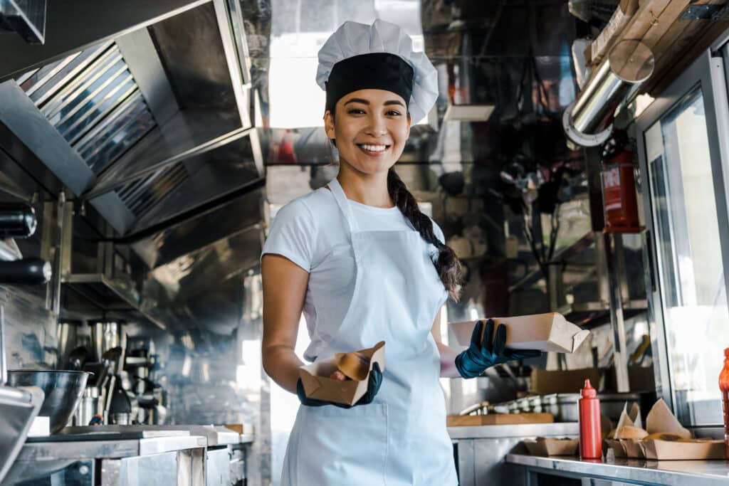 small food truck owner holding hot dog sandwich and smiling