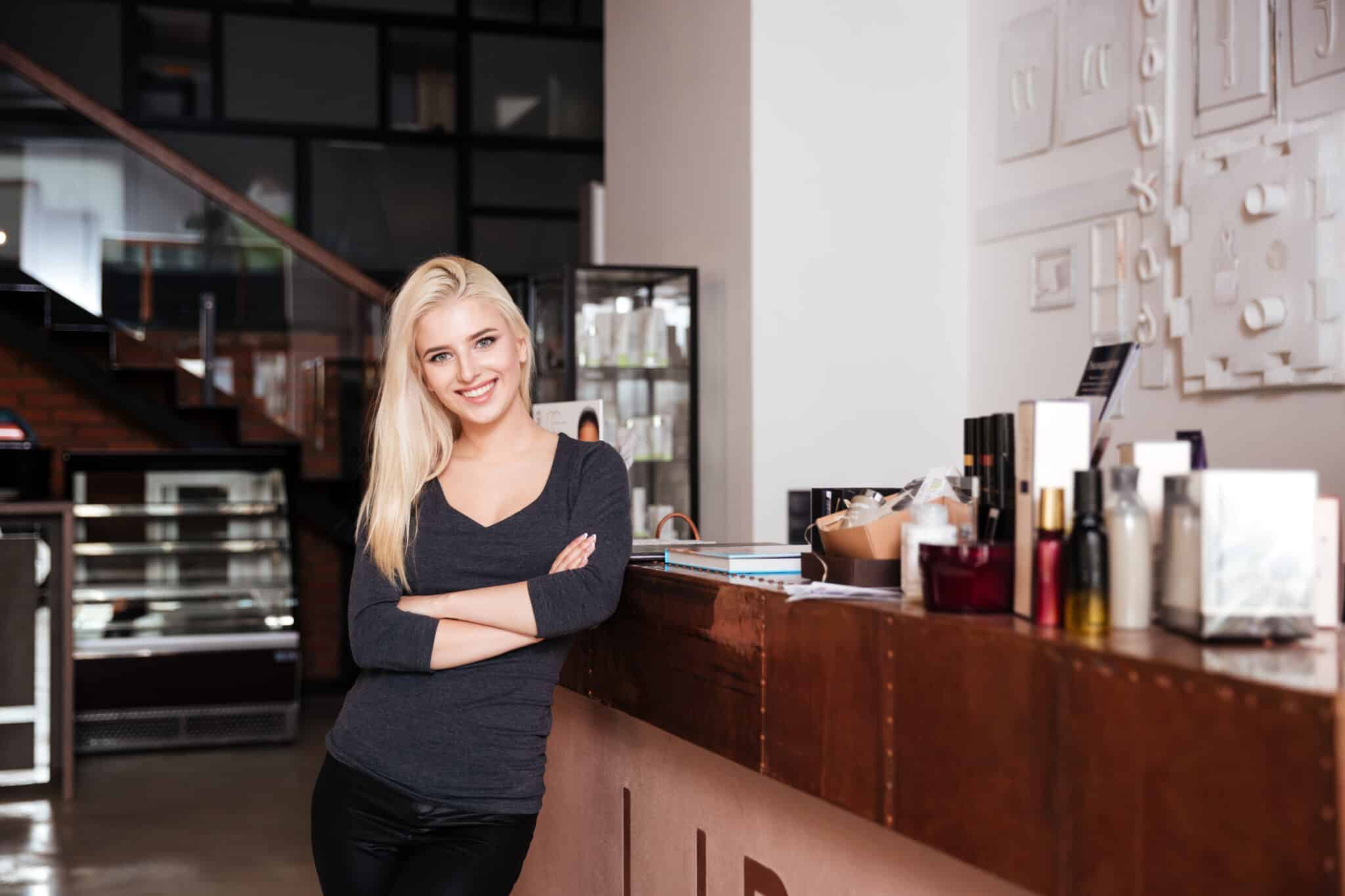 female receptionist of beauty salon standing with hands crossed