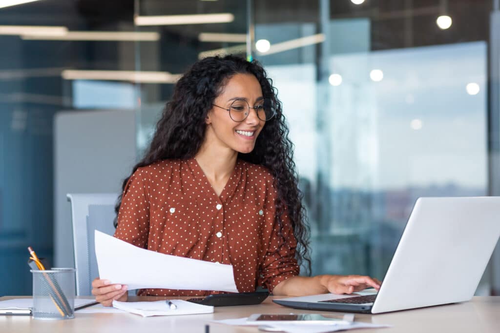 young happy secretary planning her day ahead with paper and computer