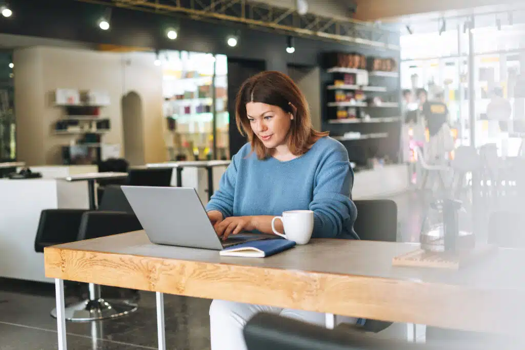 salon manager working from a laptop inside her salon on the backdrop