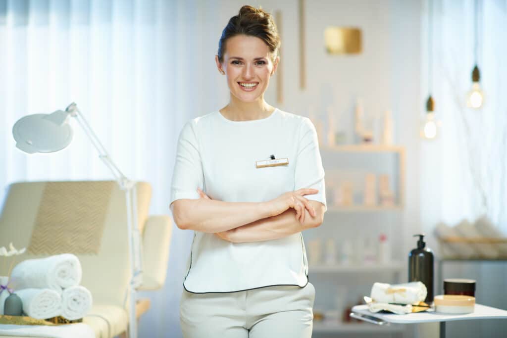 successful beauty spa business owner smiling with equipment and uniform