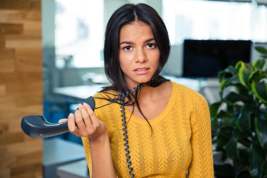 tired businesswoman holding phone in office confirming appointments