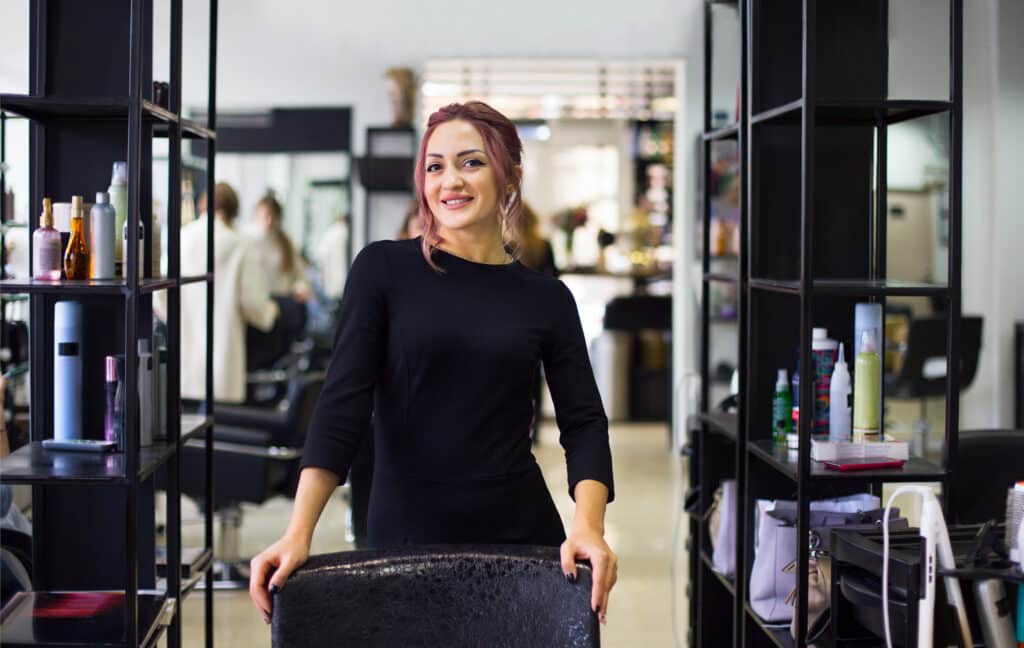 hair salon owner smiling and holding chair in a salon