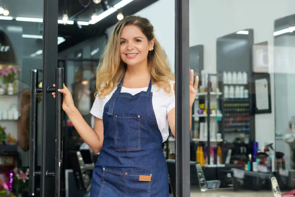 hairdresser opening salon door smiling