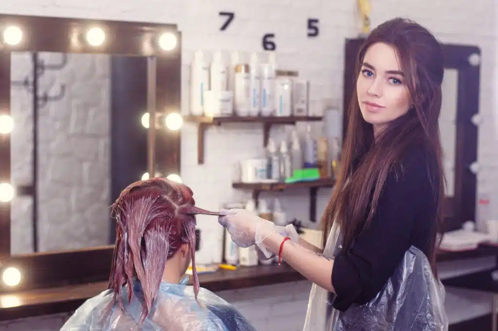 professional stylist performing hair coloring in hair salon