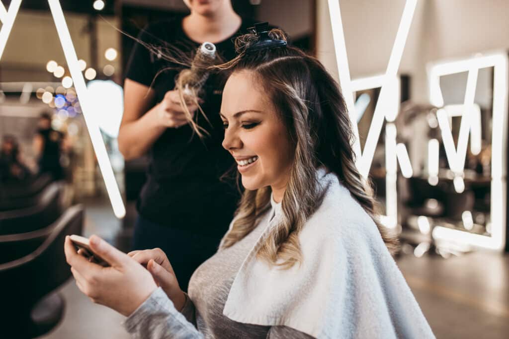 mother with long hair at the beauty salon using smart phone