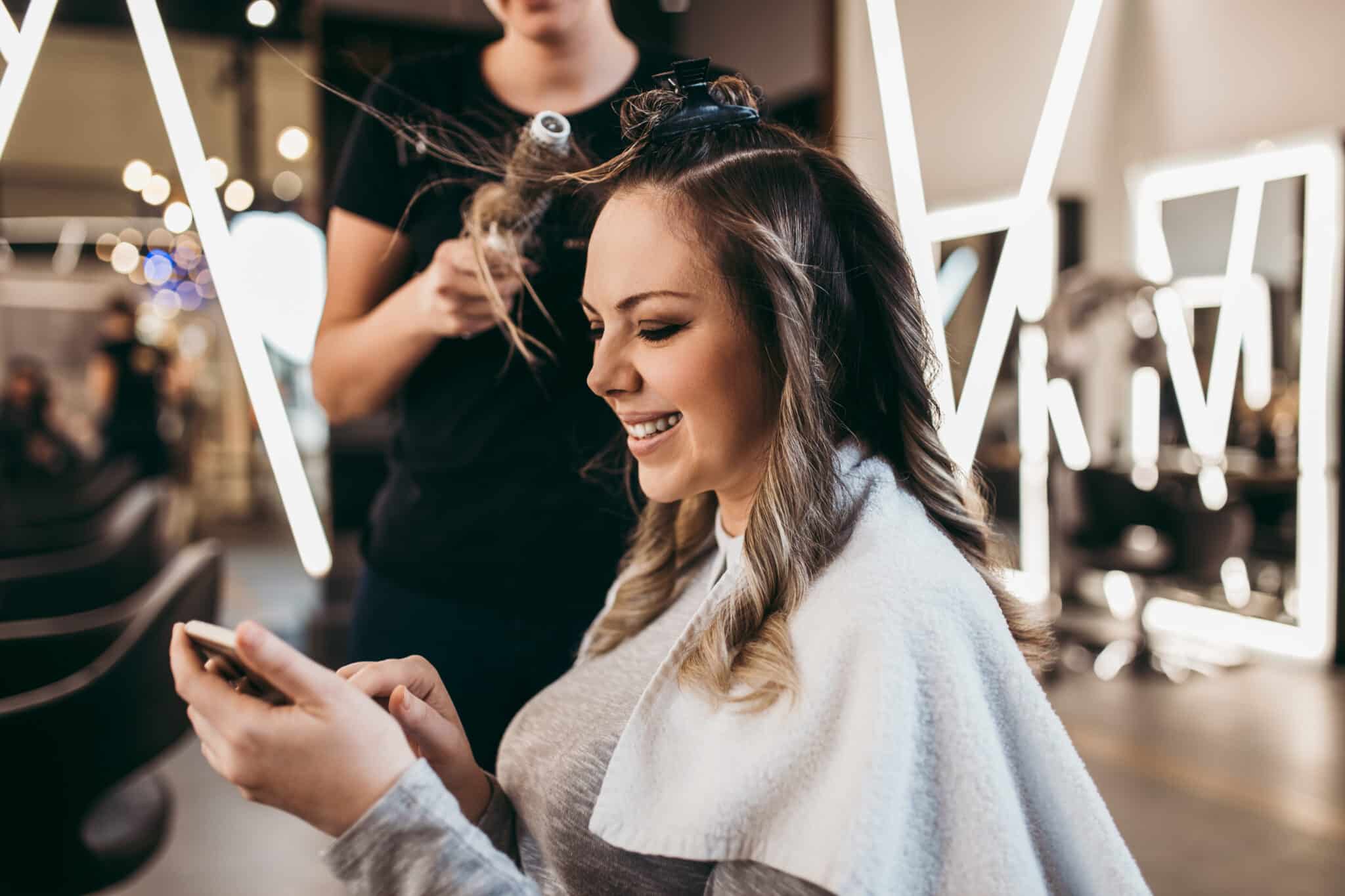 mother with long hair at the beauty salon using smart phone
