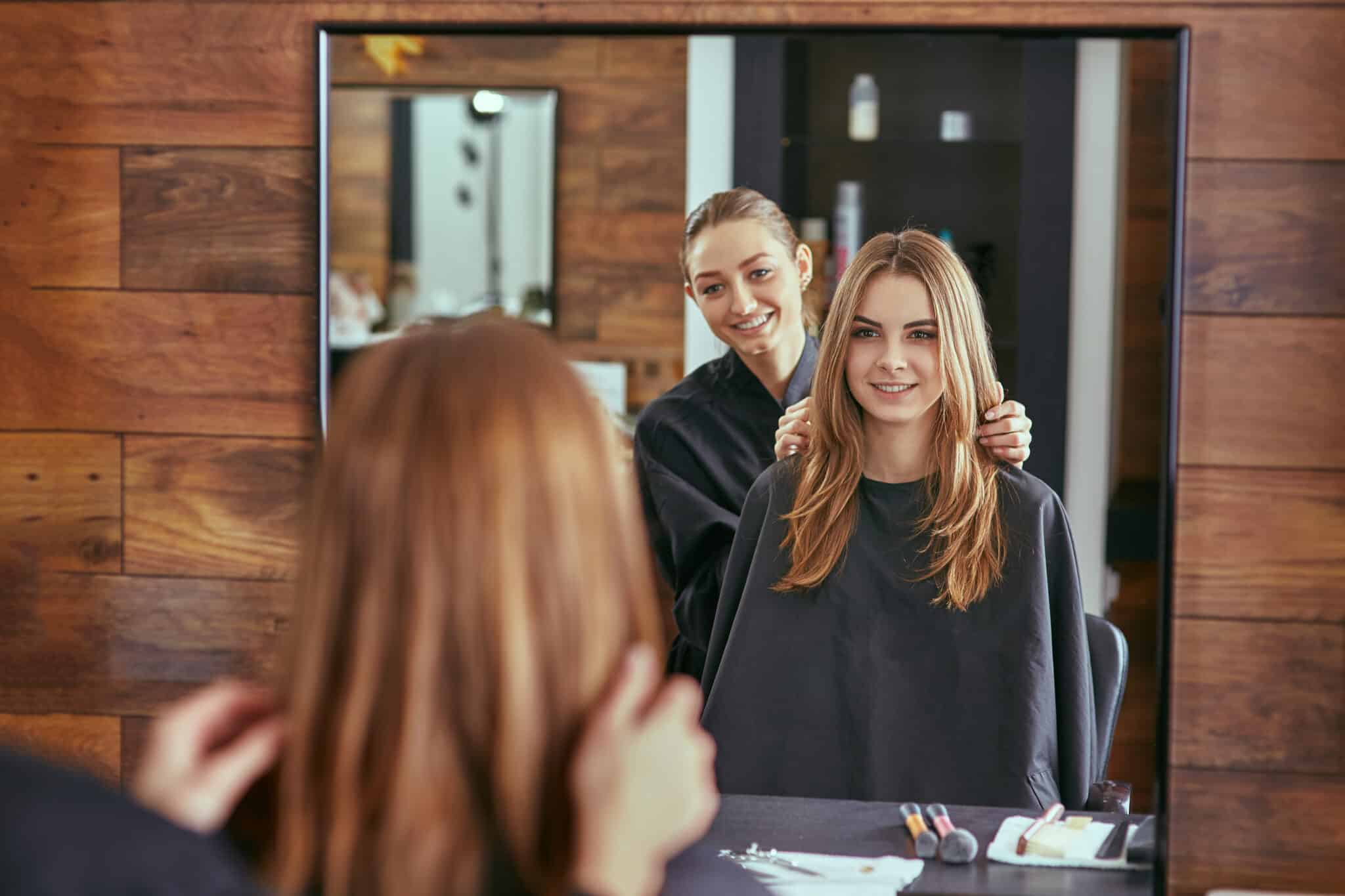 salon client smiling at the mirror with stylist behind