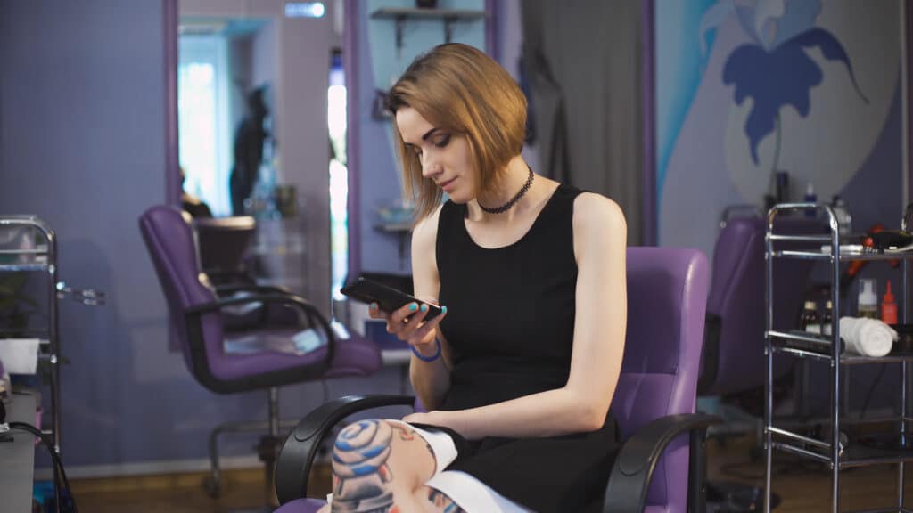 young woman receiving text message inside beauty salon