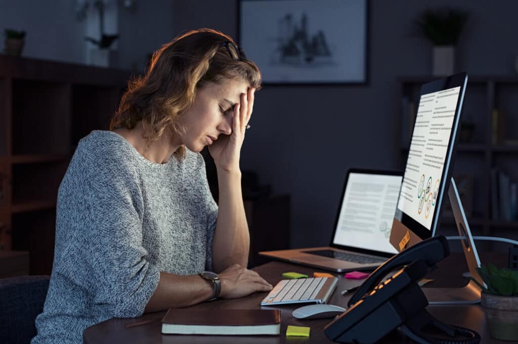 woman working at the computer feeling stressed and burnout