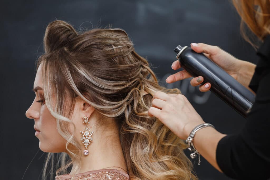 hairdresser using hairspray on client's hair at salon